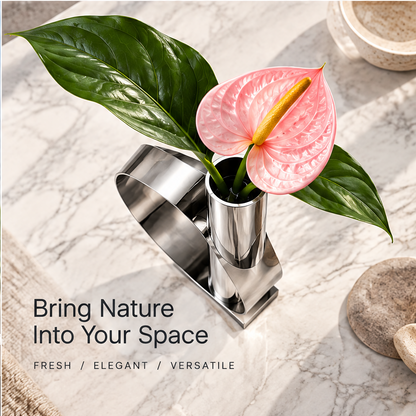 Overhead view of the silver sculptural vase with pink anthurium and green leaves beside botanical styling text